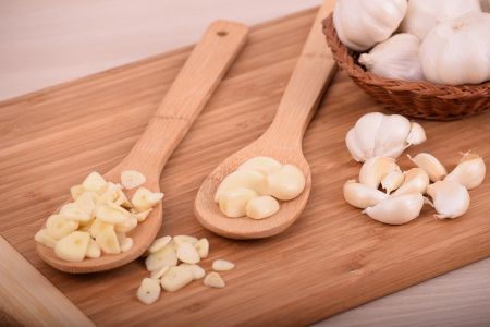Cesnak a jeho pestovanie - Hlávky a strúčiky cesnaku na drevených lyžiciach a drevenej podložke